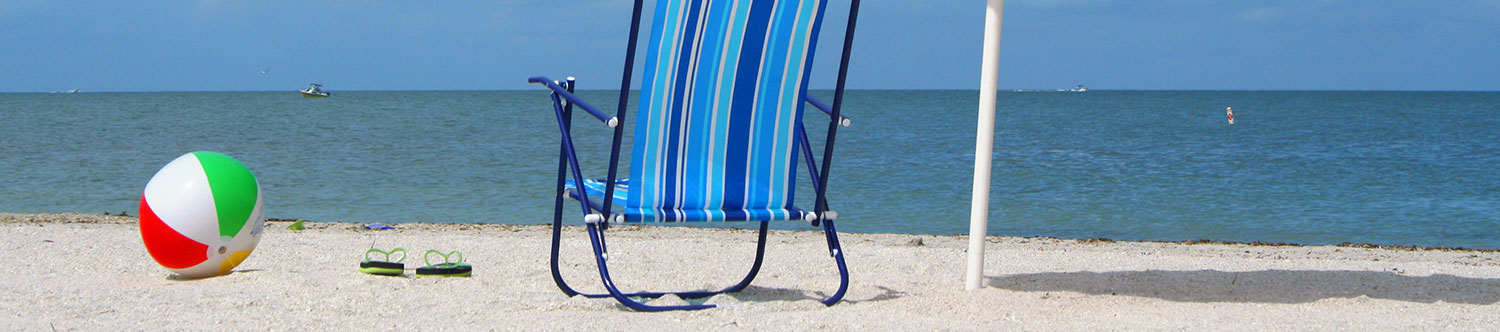 Beach ball, flip flops, and beach chair by the ocean