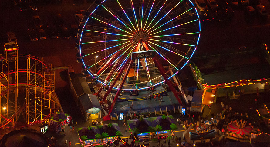 Aerial view of inlet pier amusment park and iferris wheel colorfully lit at night