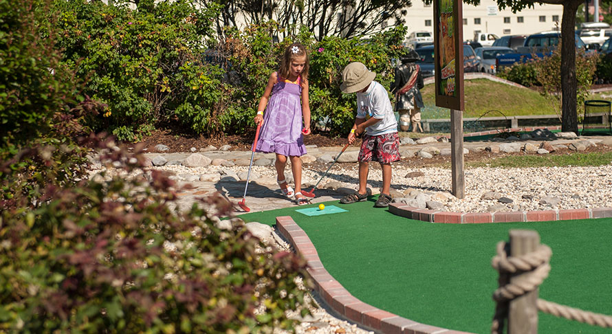 Boy and girl teeing up at miniature golf course