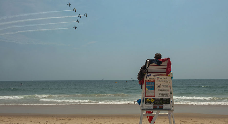 Lifeguard sitting in station overlooking beach and air show display