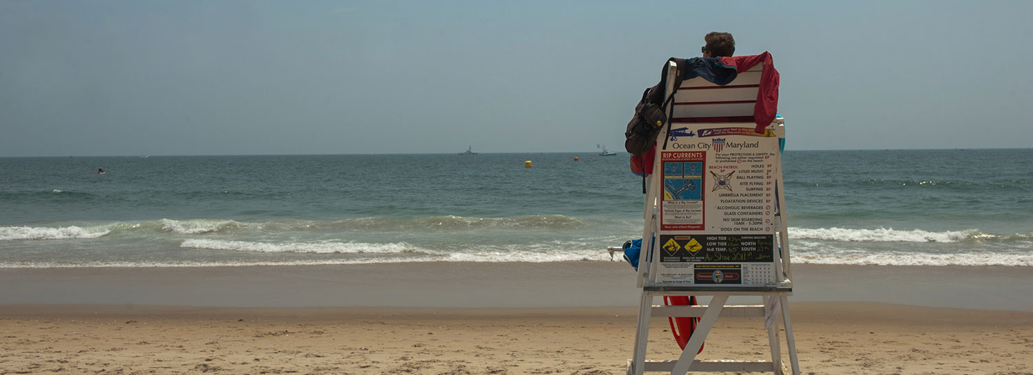 Lifeguard sitting in station overlooking crashing waves and ocean horizon