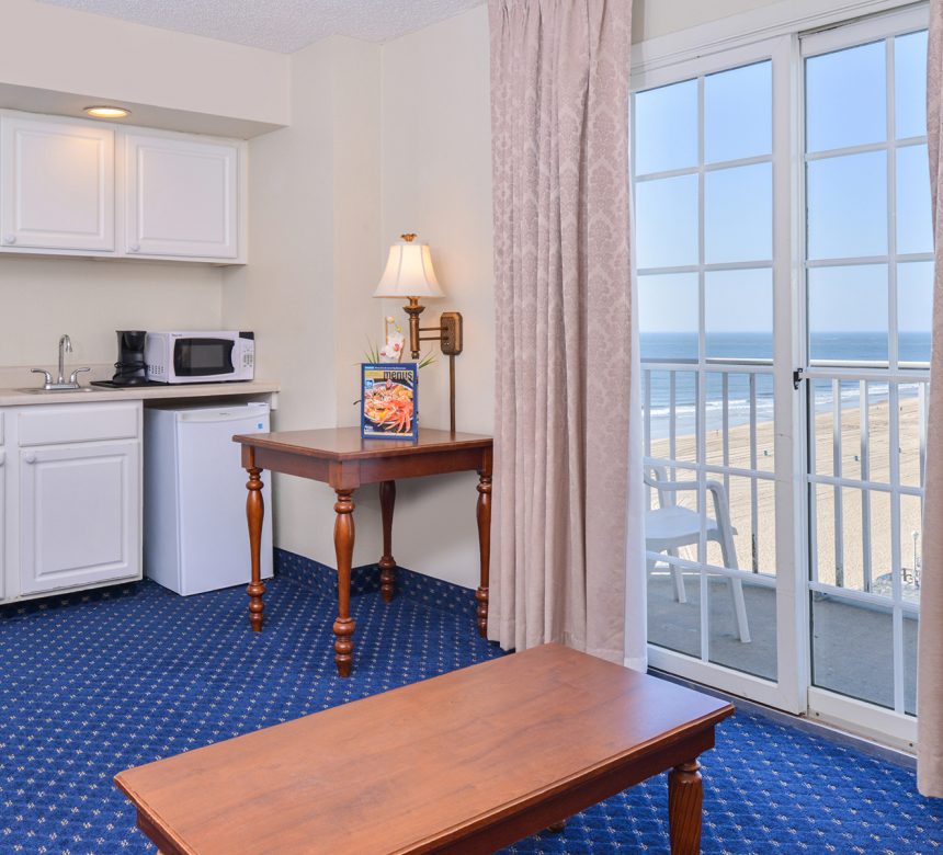 Coffee maker, small refrigerator, microwave, and doors to balcony view of beach